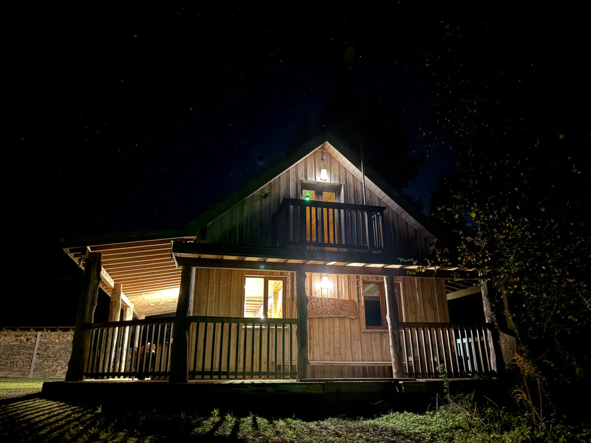 A wooden cabin at Hollyford lit up at night