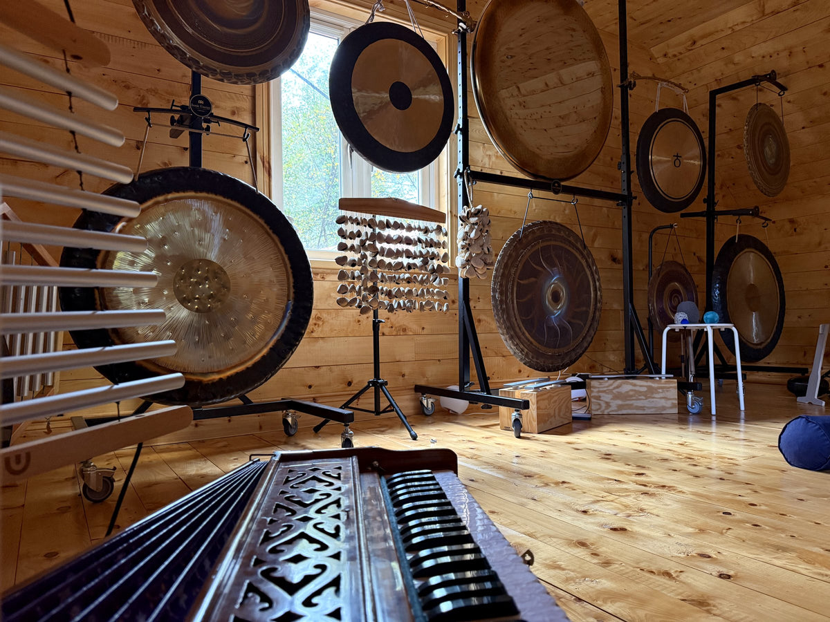 A harmonium in front of gongs and chimes in the training loft