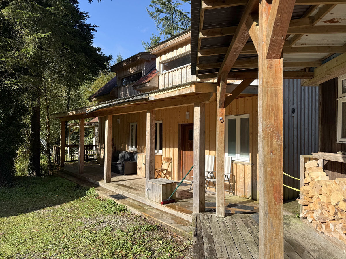The covered porch of a cabin at Hollyford with stacked firewood